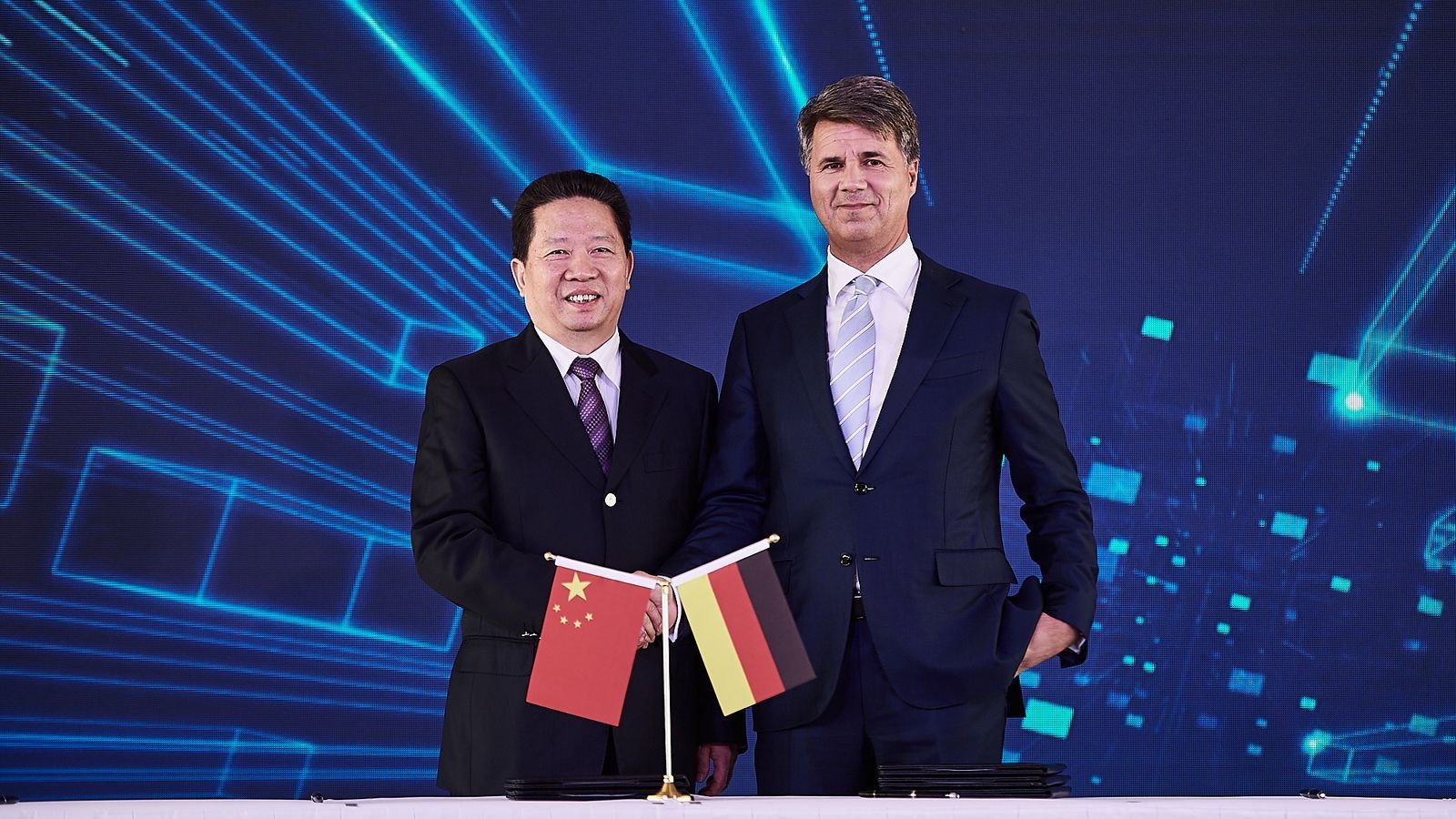 Региональный секретарь Компартии Китая в провинции Ляонин Чен Киуфа и глава BMW Харальд Крюгер жмут руки в знак достижения соглашения о сделке в рамках совместного предприятия BBA.