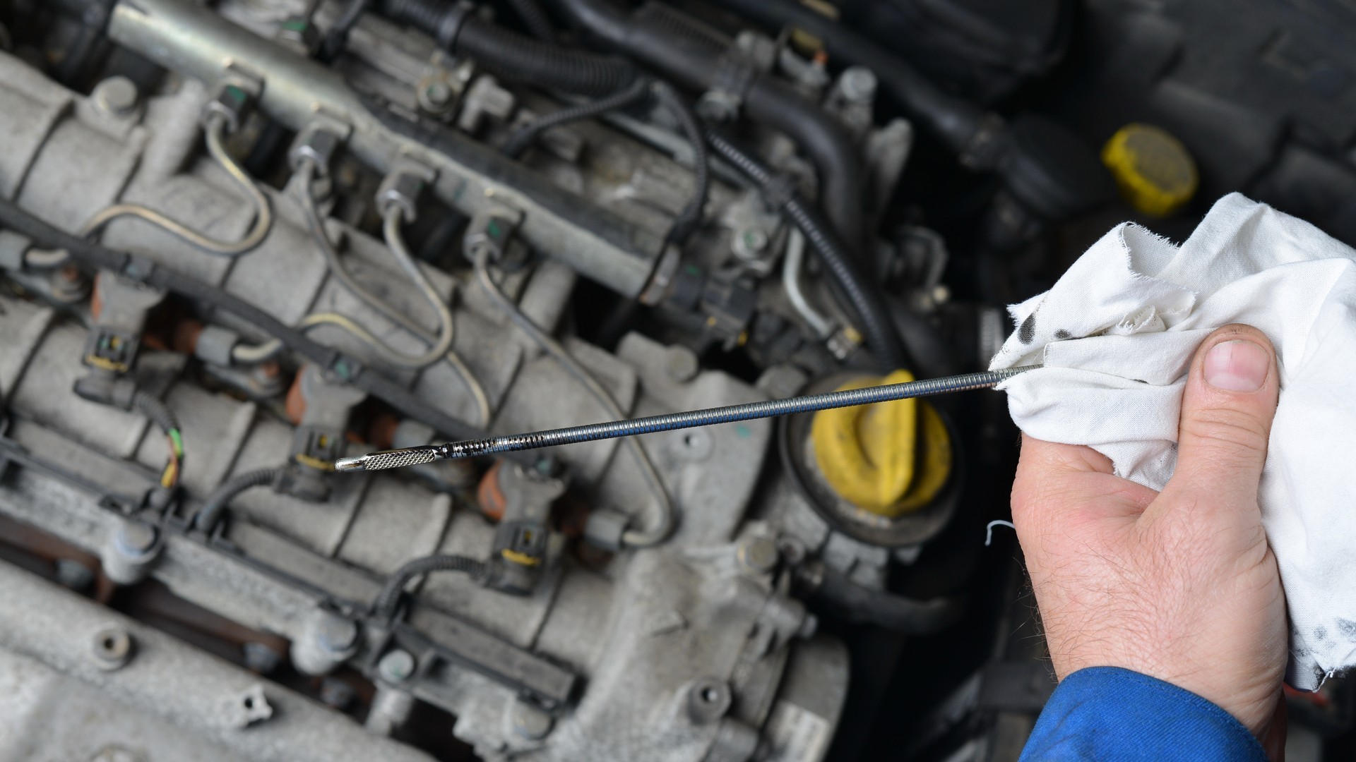 Auto mechanic checking engine oil level.